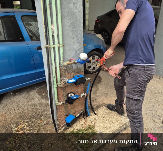 אדם עובד על צנרת מים עם כלי עבודה